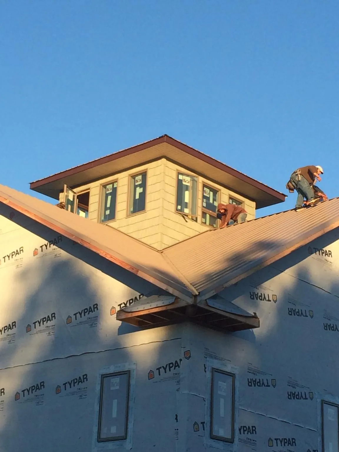 Roofers working around a rooftop cupola on a new metal roof at sunset — Roof Waterproofing in Beaver by Roofing Brothers